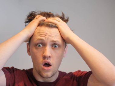 Yakışıklı bir genç adam elleri başının üstünde şoka uğramış görünüyor.