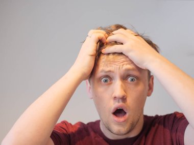 Yakışıklı bir genç adam elleri başının üstünde şoka uğramış görünüyor.