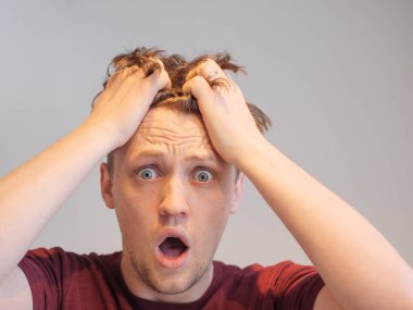 Yakışıklı bir genç adam elleri kafasında şoka uğramış görünüyor.