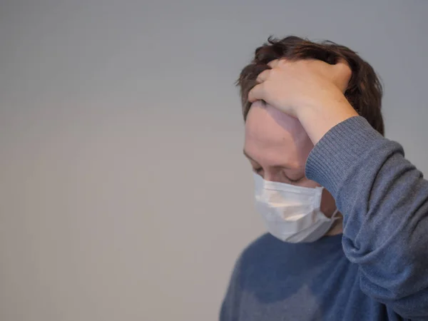 Grip olmuş genç bir adam ateşini ölçüyor.