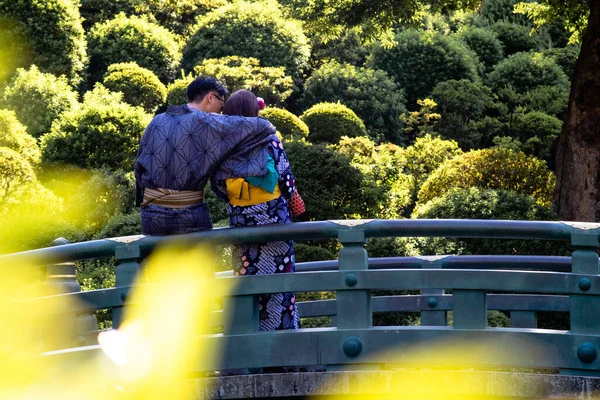 Kimono giyen genç bir çift köprüde sarılıyorlar.