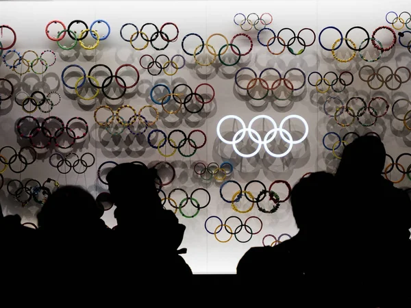 29 11 2019 - Tokyo, Japonia: Vizitatorii sunt silhoutted în fața unui zid de logo-uri olimpice — Fotografie, imagine de stoc