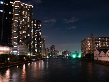 Tokyo 'daki yüksek binalar bir nehre yansıyor