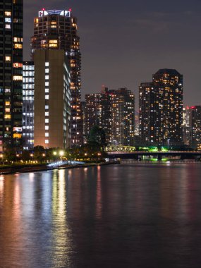 Tokyo 'daki yüksek binalar bir nehre yansıyor