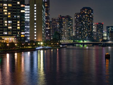 Tokyo 'daki yüksek binalar bir nehre yansıyor