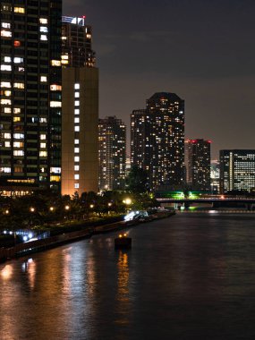 Tokyo 'daki yüksek binalar bir nehre yansıyor
