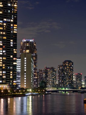 Tokyo 'daki yüksek binalar bir nehre yansıyor