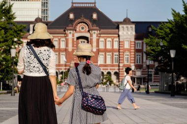 Tokyo, Japonya - 9819: Tokyo istasyonunun dışında bir anne ve kız yan yana durdu
