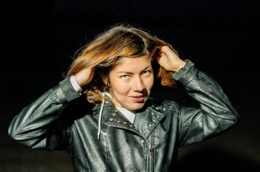  Siyah ceketli gülümseyen kız koyu renk saçlarıyla el ele tutuşuyor.