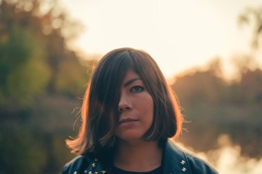  Yüzü alacakaranlıkta siyah saçlı genç bir kız doğanın arka planına karşı