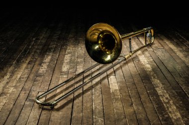 Altın pirinç enstrüman trombon kahverengi ahşap bir sahnede yatıyor.