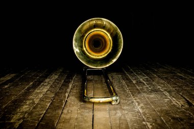 Sahnenin ahşap zemininde sarı pirinç enstrümanlı trombon vardı. Zilin önüne bak.