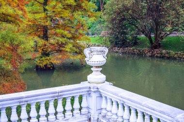Baluster ve Buen Retiro parkındaki Palacio de Cristal 'in yanındaki gölette antika bir vazo ile beyaz korkuluk. Madrid, İspanya