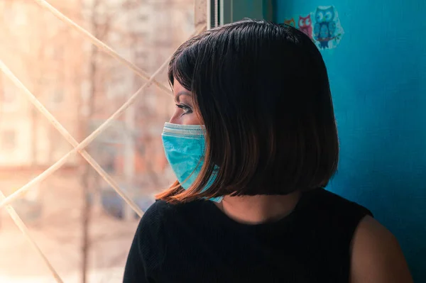 Siyah Elbiseli Esmer Bir Kız Ameliyat Maskesiyle Hastane Penceresinde Oturur — Stok fotoğraf