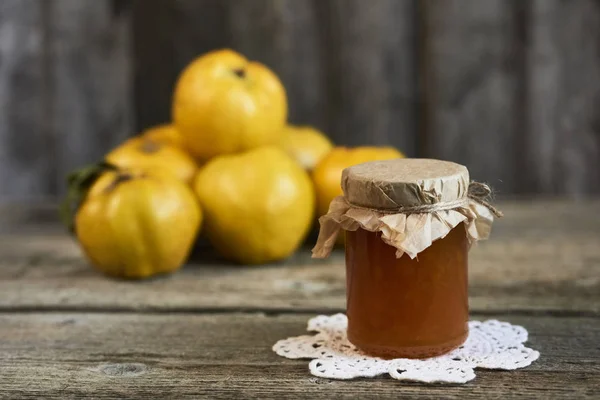 Perto de jarro de engarrafamento e marmelos com folhas em rústico de madeira — Fotografia de Stock