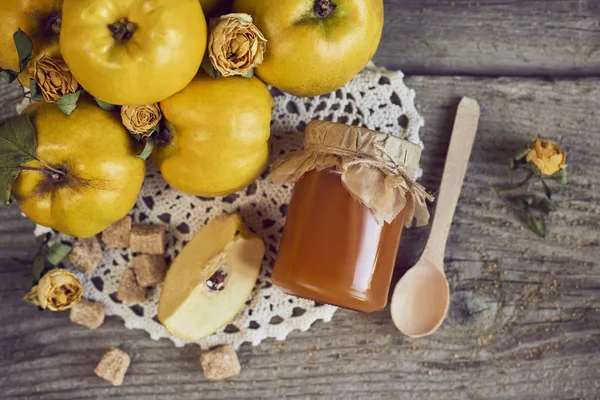 Pot de confiture avec cuillère et coings avec feuilles sur bois rustique b — Photo