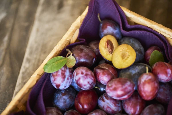 Ciruelas Frescas Con Hojas Verdes Canasta Mimbre Sobre Mesa Madera — Foto de Stock