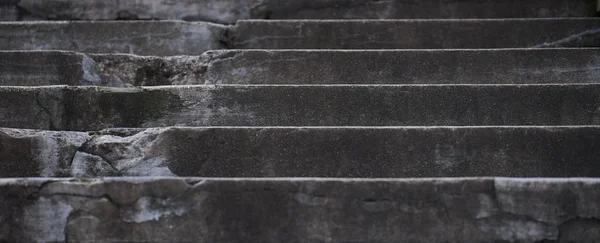 Closeup of old stairs. Dark grey textured concrete stairs background