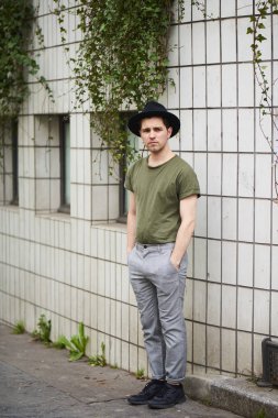 Portre yakışıklı şık adam giyen siyah şapka ayakta Botanik Bahçesi tuğla duvara sakallı