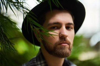 Botanik Bahçesi siyah şapka ayakta giyen Closeup sakallı portre yakışıklı şık adam arka plan bulanık