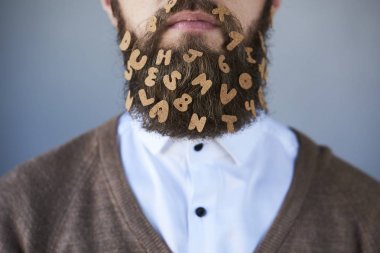 Closeup of handsome bearded man with letter stickers on gray background clipart
