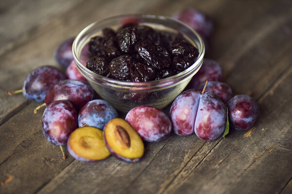 Dried plums or prunes in bowl on wooden background 