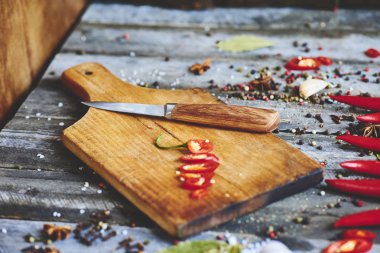 Kesme tahtası, baharat, fesleğen, roka, domates ve bıçak, üstten görünüm ile doğranmış kırmızı biber