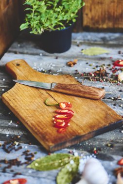 Kesme tahtası, baharat, fesleğen, roka, domates ve bıçak, üstten görünüm ile doğranmış kırmızı biber