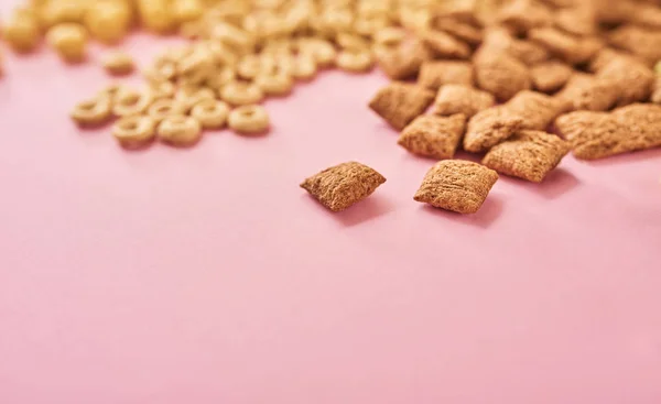 粉红色背景下不同类型的玉米片或谷物 — 图库照片