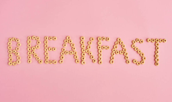 Слово Завтрак на розовом фоне, вид сверху
.