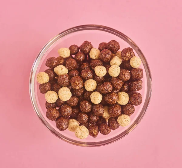 Closeup of glass bowl of cereals on pink background