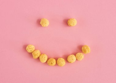 Gülümsemesi flakes veya tahıl pembe bir arka plan üzerine yapılmış