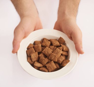 Mısır gevreği veya beyaz arka plan üzerinde izole tahıllar ile plaka tutan adamın el closeup