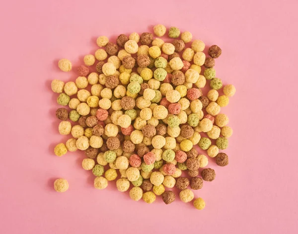 Pile of cornflakes or cereal on pink background, top view