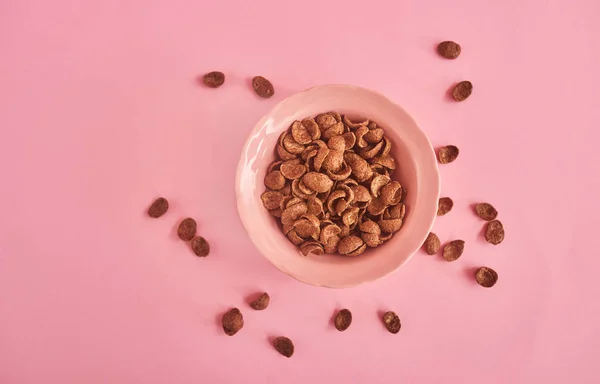 Pink plate of cereals on pink background, top view