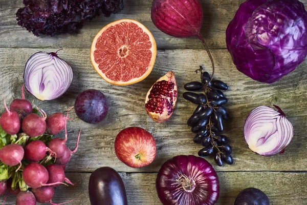 Assorted types of purple fruits and vegetables on wooden backgro