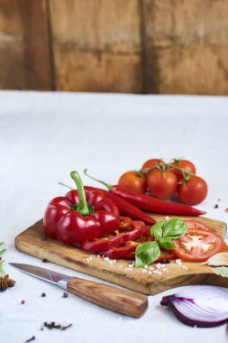 Doğranmış kırmızı biber baharat, fesleğen, roka, domates, bıçak ve kırmızı pul biber, üstten görünüm ile kesme tahtası üzerinde