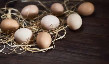 Saman ahşap arka plan üzerinde kahverengi taze tavuk yumurta.