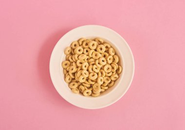 Pembe bir arka plan üzerinde bej Mısır halkalar ile beyaz plaka Üstten Görünüm