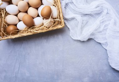 Mavi beton zemin üzerine taze çiğ tavuk yumurta saman ve tülbent ile hasır sepet içinde üstten görünüm. 