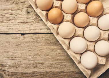 Tavuk taze çiğ yumurta parlak kahverengi ahşap masa arka plan üzerinde yumurta karton kutuda Üstten Görünüm.