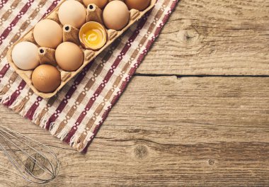 Tavuk taze çiğ yumurta ile mutfak havlusu parlak kahverengi ahşap masa arka plan üzerinde yumurta karton kutuda görünümünü yakın çekim. 