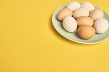 Taze çiğ tavuk yumurta Sarı zemin üzerine yeşil plaka.