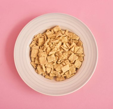 Beyaz plaka kare Mısır pedleri ile üstten görünüm pembe bir arka plan üzerinde