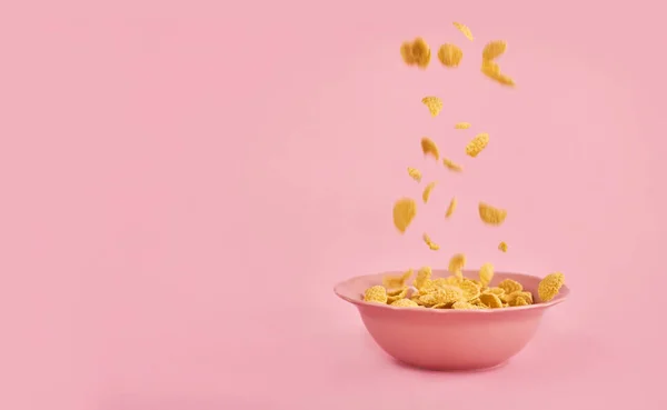 Cereals falling on pink plate over pink background