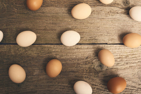 Close-up view of chicken fresh raw eggs over bright brown wooden table background.