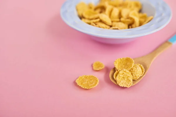 Blue plate of cereals and spoon on pink background