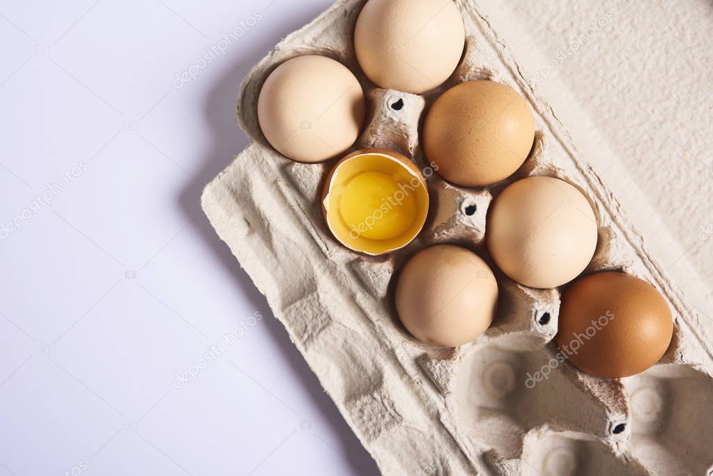 Top view of fresh brown chicken eggs in carton box isolated on white background