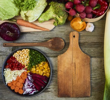 Ahşap arka plan üzerinde kesme tahtası ile taze çiğ sebze