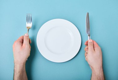 Erkek el ile çatal ve boş üstten görünüm yuvarlak masada plaka